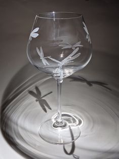 a wine glass sitting on top of a table next to a shadow of a dragonfly