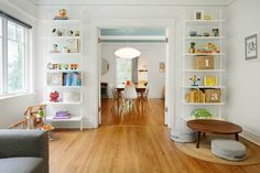 a living room filled with furniture and bookshelves next to a dining room table