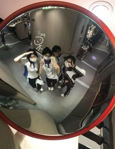 a group of young people standing in front of a mirror with their reflection on it