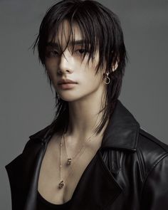 a young man with black hair and piercings wearing a leather jacket, posing for the camera