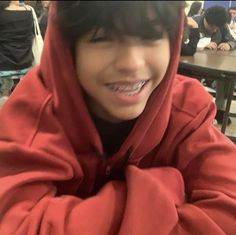 a boy in a red hoodie sitting at a table