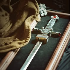 a cross and two swords are laying on the floor next to each other in a wooden box