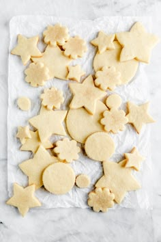 some cut out cookies are sitting on a piece of wax paper with stars and moon shapes