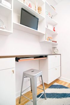 a white desk with a computer monitor on top of it and a stool in front of it