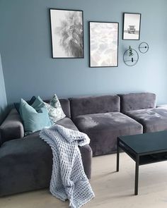 a living room with grey couches and pictures on the wall above them, along with a coffee table