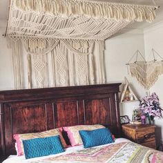 a bedroom with a bed, dresser and macrame hanging from the ceiling