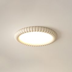 a circular light fixture mounted on the ceiling in a room with white walls and flooring