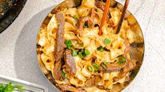 a bowl filled with noodles and meat on top of a table