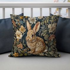 a decorative pillow with a rabbit on it's side and flowers in the background