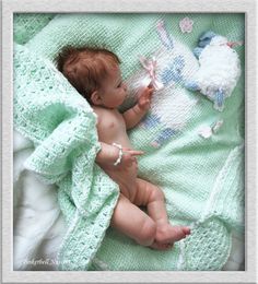 a baby laying on top of a blanket next to a stuffed animal