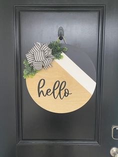 a black door with a wooden sign that says hello on it and a bow in the center