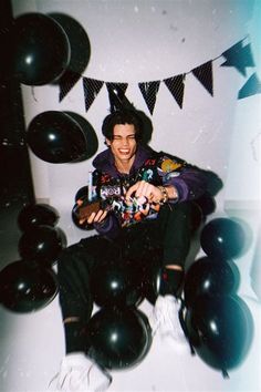 a man sitting on the floor surrounded by balloons