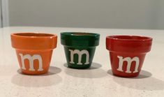 three ceramic cups with the letter m on them