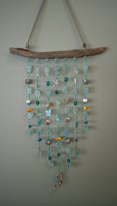 a piece of driftwood with beads hanging from it's side on the wall