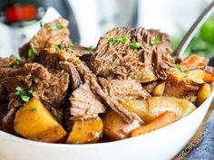 a white bowl filled with meat and potatoes