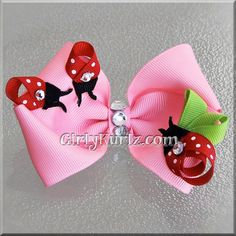 two pink bows with black cats and red polka dots on the top, one has a green bow