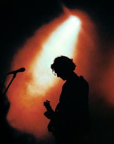 the silhouette of a person standing in front of a microphone and holding a cell phone