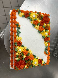 a cake with flowers on it sitting on top of a metal table in a kitchen