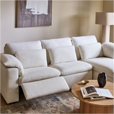 a living room with a sectional couch and coffee table in front of a painting on the wall