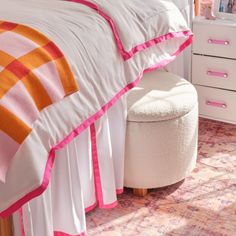 a white bed with pink and orange bedspread on top of it in a bedroom