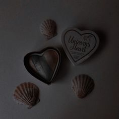 three seashells and a heart shaped cookie on a white surface with the words unicorn's heart written on it