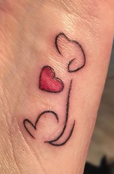 a small heart tattoo on the foot of a woman's left leg, with two hearts