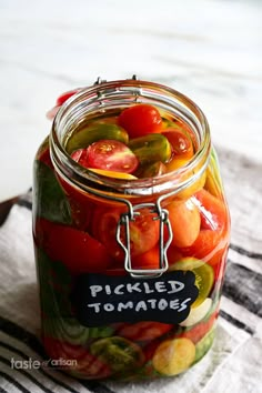 a jar filled with pickled tomatoes on top of a table