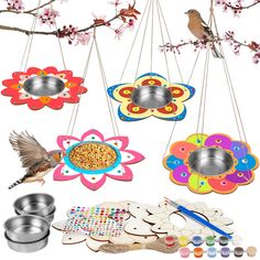 bird feeders hanging from the branches with flowers and birds eating out of bowls on them