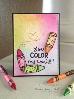 some crayons are sitting next to a card that says, you color my world