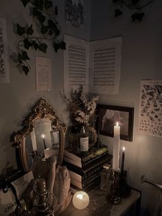 a table with books, candles and pictures on the wall in a dimly lit room