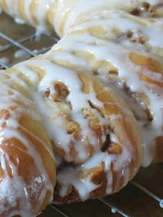 glazed donuts sitting on top of a cooling rack covered in icing and nuts