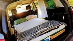 the back end of a van with a bed in it's cargo area and windows open