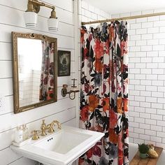 a bathroom with a sink, mirror and shower curtain covered in floral print fabric next to a white brick wall