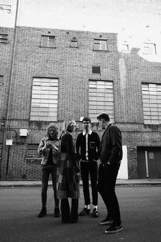 four people standing in front of a brick building