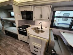 a kitchen area with sink, stove and cabinets in a recreational travel trailer at night