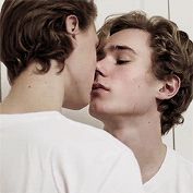 two young men kissing each other in front of a mirror