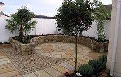 a stone patio with trees and plants in the center, surrounded by graveled walkways