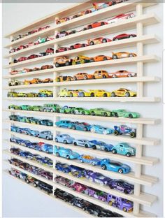 a wall mounted shelf filled with lots of toy cars