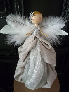 an angel figurine sitting on top of a wooden stand with white feathers around it