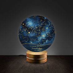 a night sky globe with stars on it and a wooden base in front of a dark background