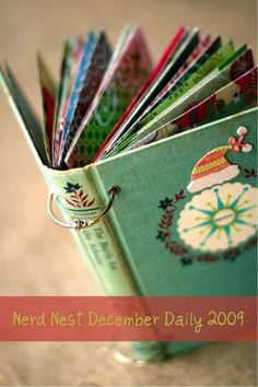 an open book with christmas designs on it sitting on top of a wooden table next to a pair of scissors