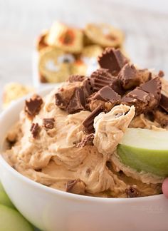 a bowl filled with peanut butter and an apple next to some crackers on the side