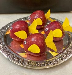 apples decorated with yellow and red paper birds on a silver plate