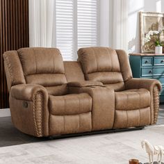 a brown reclining couch sitting in a living room next to a blue dresser and window