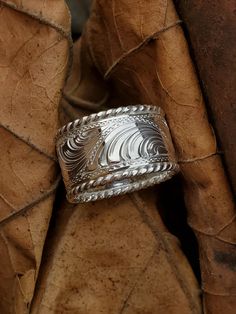 a silver ring sitting on top of a leaf