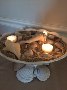 candles are lit in the center of a cake plate with shells and seashells on it