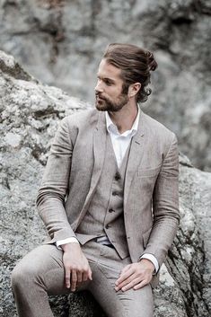 a man sitting on top of a rock wearing a suit