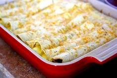 a red casserole dish filled with cheese and tortilla shells on a counter