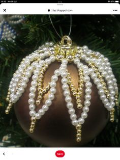 a christmas ornament with pearls hanging from it's side on a tree