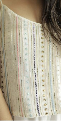 a close up of a woman's shoulder wearing a white top with multicolored stripes